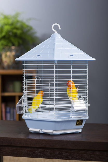 A light blue plastic bird cage with white wire bars, featuring two small yellow birds perched inside, set on a dark wooden table against a blurred gray background.